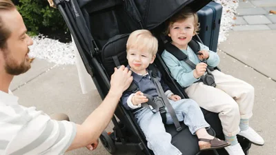 Two children seated in the UPPAbaby Minu Duo stroller with visible side-by-side seating and harnesses
