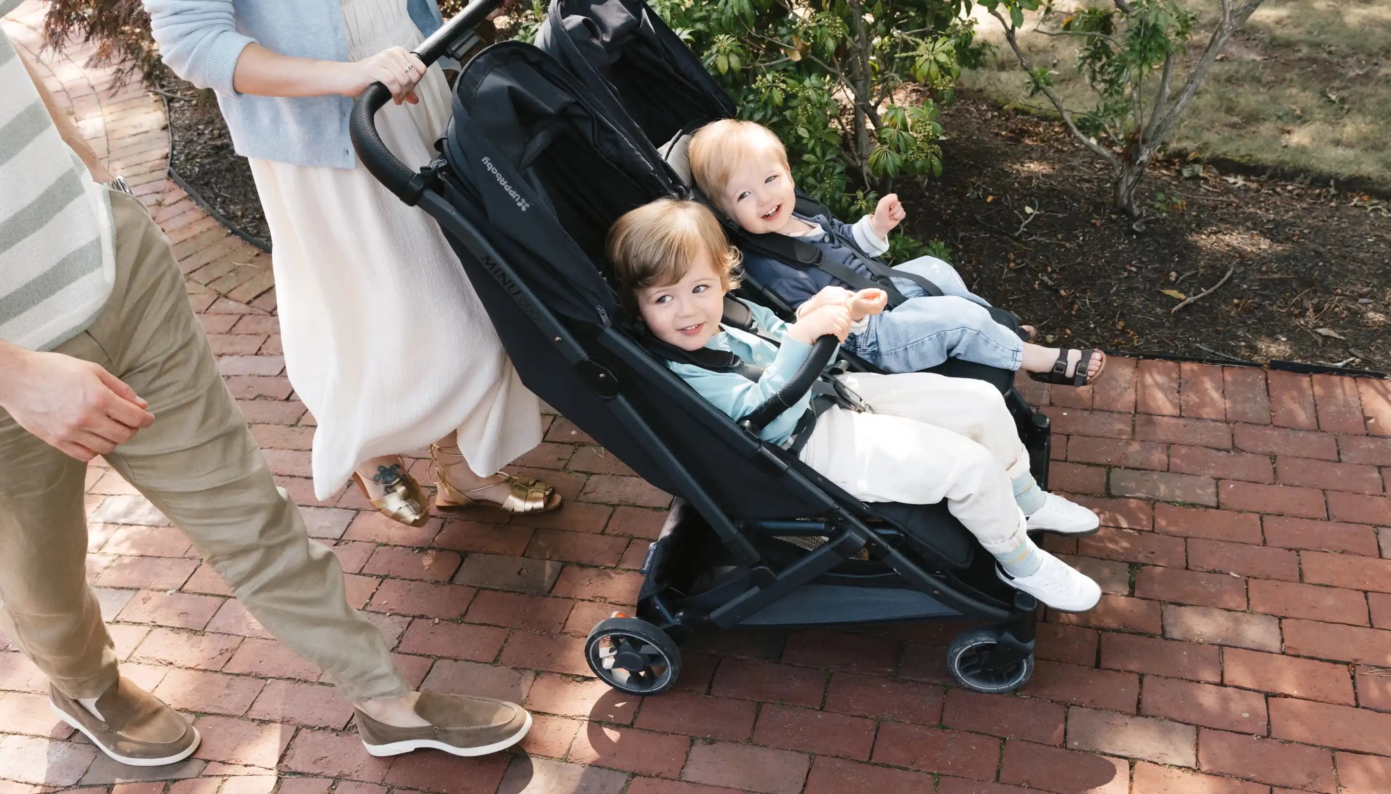 parents pushing two children in black double stroller